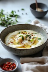 Creamy Bowl of Grits with Fresh Herbs and Spices on Table