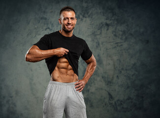 Handsome Muscular Man In Black T-Shirt Showing his Abdominal Muscles