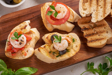 Olives, oil, Grilled shrimps and fresh vegetable salad on a wooden board on black slate stone board...