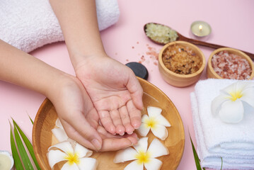 Woman soaking her hands in bowl of water and flowers, Spa treatment and product for female feet and...