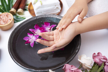 Woman soaking her hands in bowl of water and flowers, Spa treatment and product for female feet and...