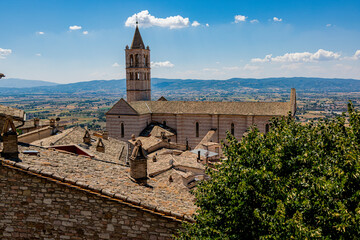 Rooftop view of the Basilica of Saint Clare in Assisi, Italy, overlooking the Umbrian valley under...