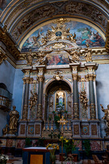 A view of the Temple of Minerva and the adjacent medieval clock tower in the historic center of Assisi, under a clear blue sky
