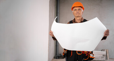 civil engineer or builder with paper house project checking and planning at construction site, Elderly man holding blueprint