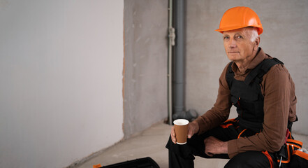 Builder with Coffee. Elderly engineer or construction worker relax on break at construction site