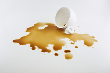 The spilled coffee from the sloppy glass is on the white floor.