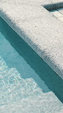 Clear blue water in the pool. Steps into the pool. The edge of the pool is finished with a gray curbstone. Relaxation in the backyard of a country house
