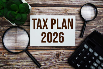 Tax plan 2026 with magnifying glass on wooden background