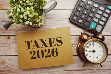 Taxes 2026 typography text with calculator on wooden background