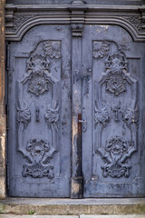 Antique blue wooden door with ornate carved floral decorations and peeling paint