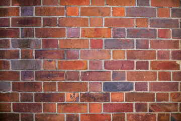 Colorful red, orange, and purple vintage brick wall with aged texture and weathered surface.