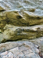 A detailed close-up of the surface of a natural rock showing its layered structure and natural...