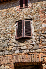 Aged wooden door on a stone facade in Monteriggioni, Tuscany, with hanging laundry and plants