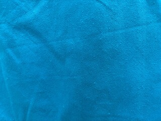 Blue slightly wrinkled fabric texture top view, close-up of textile folds and creases, soft cloth...