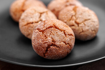 Fresh baked ginger snap cookies with cracked crumbly texture on black ceramic plate. Macro shot. 