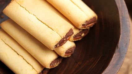 Sweet fig bar cookies with chocolate filling in wooden brown bowl. Macro shot. 