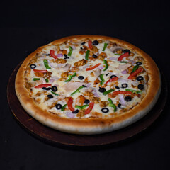 Chicken Supreme oven baked pizza on a wooden board on the dark background