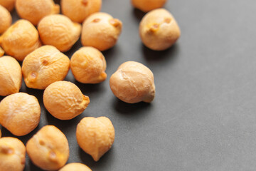 Dried chickpeas (garbanzo beans) on black ceramic plate surface. Macro shot