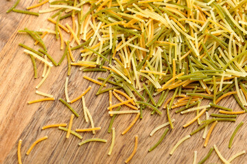 Colored angel hair vermicelli on rustic wooden surface. Italian uncooked pasta. Top view