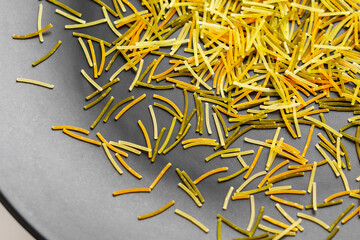 Thin multi colored vermicelli on black ceramic surface. Uncooked dry ingredient of Mediterranean...