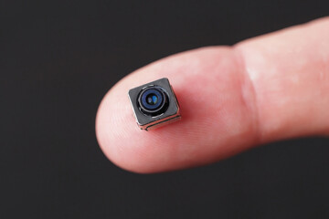 Miniature camera with tiny lens in hand, showcasing its intricate details and technology.