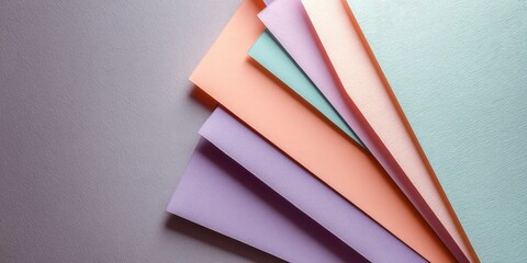 Top-down view of pastel paper sheets layered with geometric composition, soft shadows, copy space