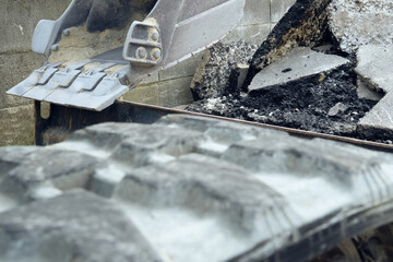 油圧ショベルのバケットとゴム製クローラーとアスファルトの廃材