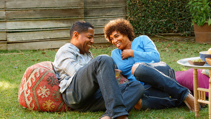 Smiling Mature Couple Enjoying Drinks And Snacks In Backyard Garden Together