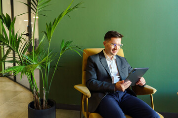 Business Professional Engaging in Digital Work While Seated Comfortably in a Modern Office Environment Surrounded by Greenery