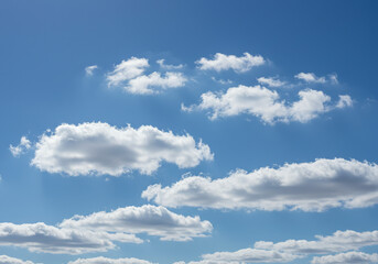 Fototapeta premium The bright blue sky is dotted with scattered white clouds, creating a serene and airy scene