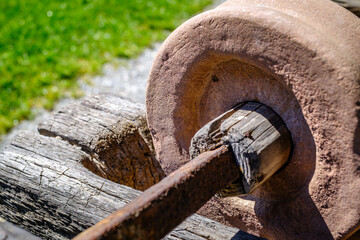 Historical stone wheel used for grinding grains in a rustic farming setting during daylight hours in an outdoor environment