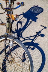 Vintage blue bicycle leaning against a colorful wall in bright sunlight during afternoon hours in an urban setting