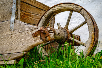 Vintage wooden cart with large wheels resting on a dusty floor in a rustic barn environment during the late afternoon light