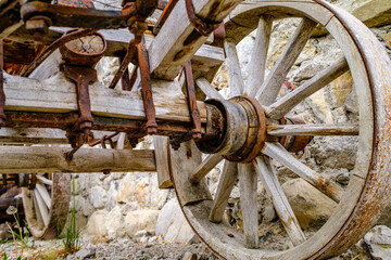 Vintage wooden cart with large wheels resting on a dusty floor in a rustic barn environment during the late afternoon light