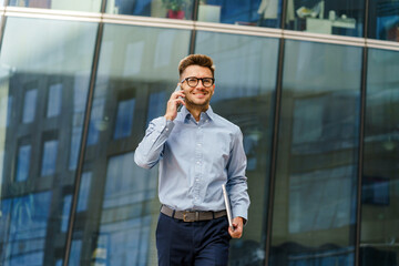 Confident Professional Walks Along a Modern Building While Engaging in a Phone Conversation on a...