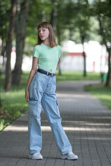 Young beautiful long-haired red-haired girl posing in a city park.