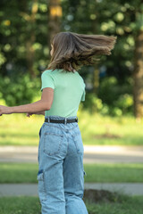 Young beautiful long-haired red-haired girl posing in a city park.