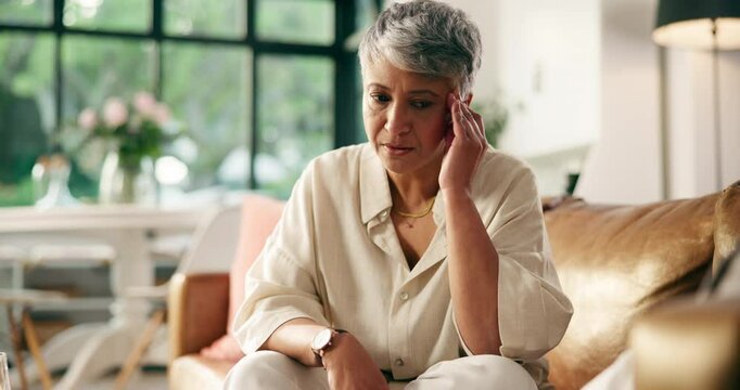 Senior, woman and headache of stress on sofa with discomfort, massage temples and brain fog. Retirement, old person and tension migraine in house with high blood pressure, hypertension and vertigo