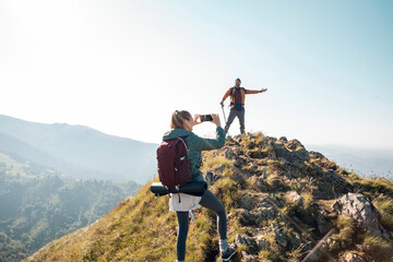 Hiking couple taking pictures on mountain peak