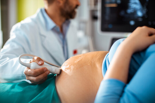 Pregnant woman getting ultrasound at doctor's office smiling during prenatal checkup