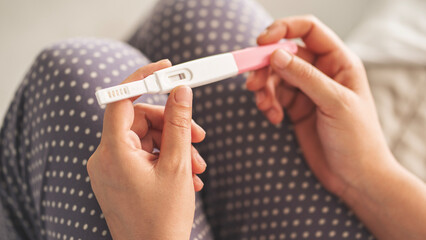 Young woman holding pregnancy test with negative result