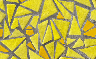 Broken tiles mosaic made with yellow ceramic pieces background texture for design.Colorful cracked...