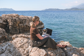 Female digital nomad working remotely from a cozy place in nature Remote work, sustainability,...