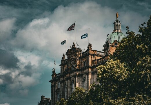 Historic Edinburgh building with flags and cloudy sky