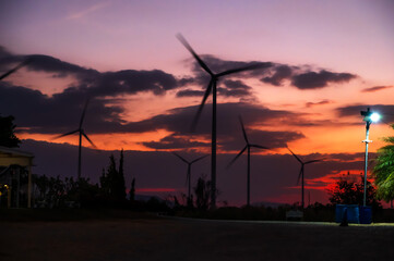 Silhouette wind turbines at sunset