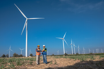 Asian wind turbine engineer man and woman working together in outdoor wind turbine power plant 