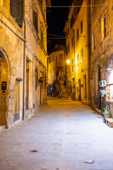 Obraz premium A nighttime view of Pitigliano, a charming Tuscan village perched on cliffs, glowing with warm lights and rich in medieval atmosphere