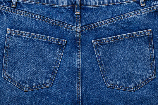 Back side of dark blue jeans with symmetrical pockets, textured textile background
