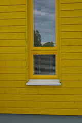 Things objects, house with yellow facade, beautiful apartment with lawn. Large street yellow plastic windows with built-in white blinds. Beautiful, stylish facade, construction, repair.