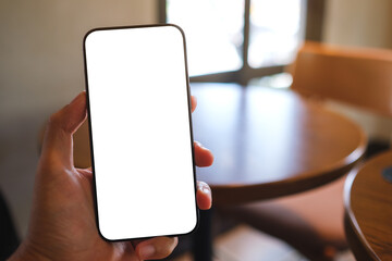 Mockup image of a man holding mobile phone with blank white screen in cafe